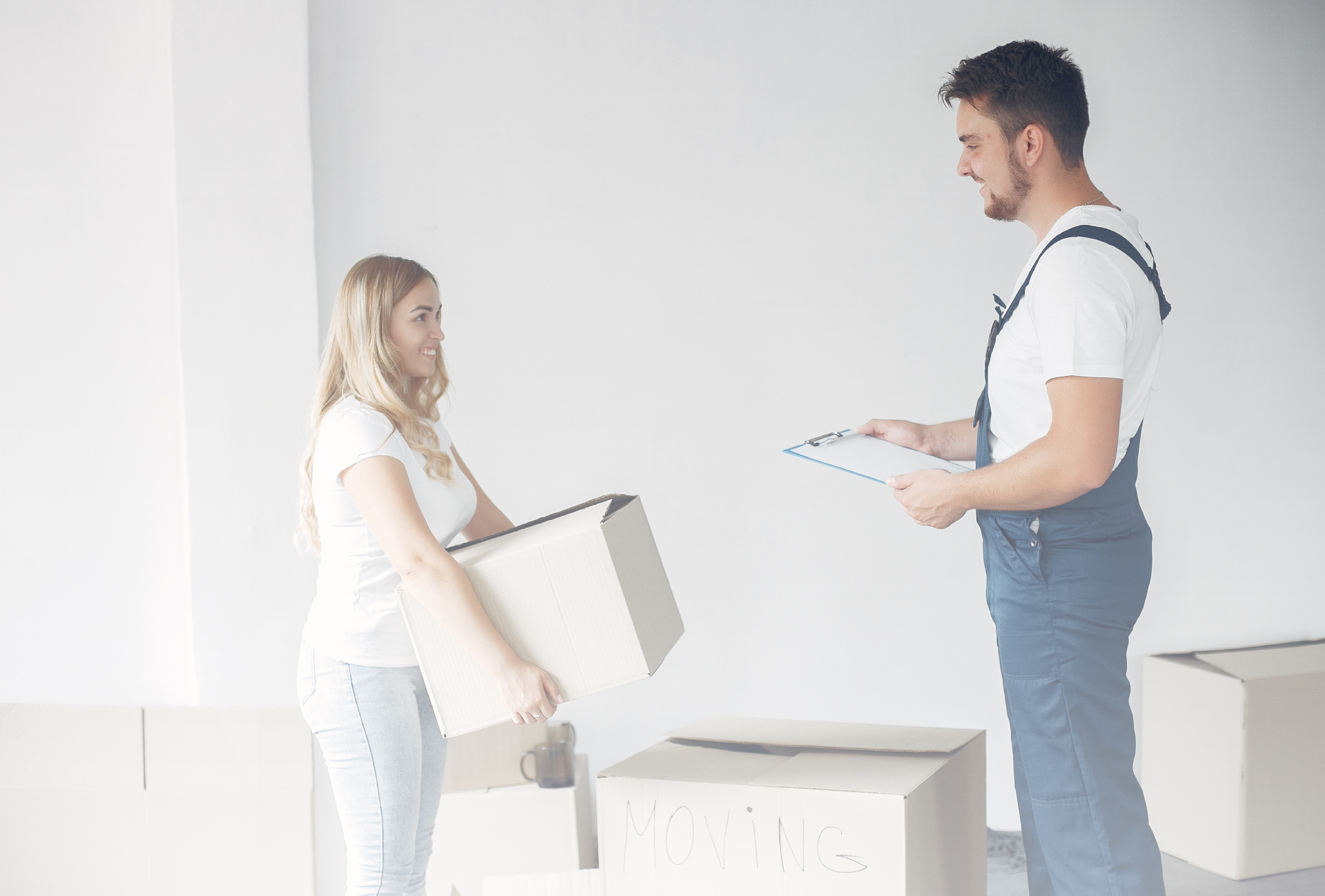 A woman packing kitchen items is watching thankfully a moving helper